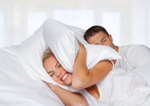 Snoring. Couple in bed while the woman is trying to sleep